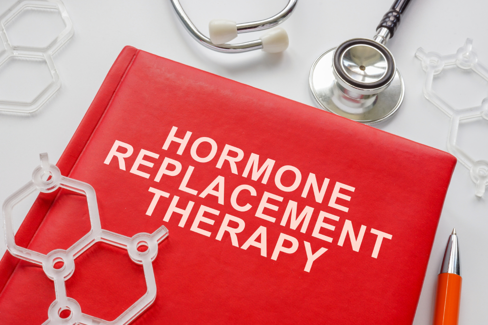 A stethoscope on a table next to a red book with “Hormone Replacement Therapy” written on it.